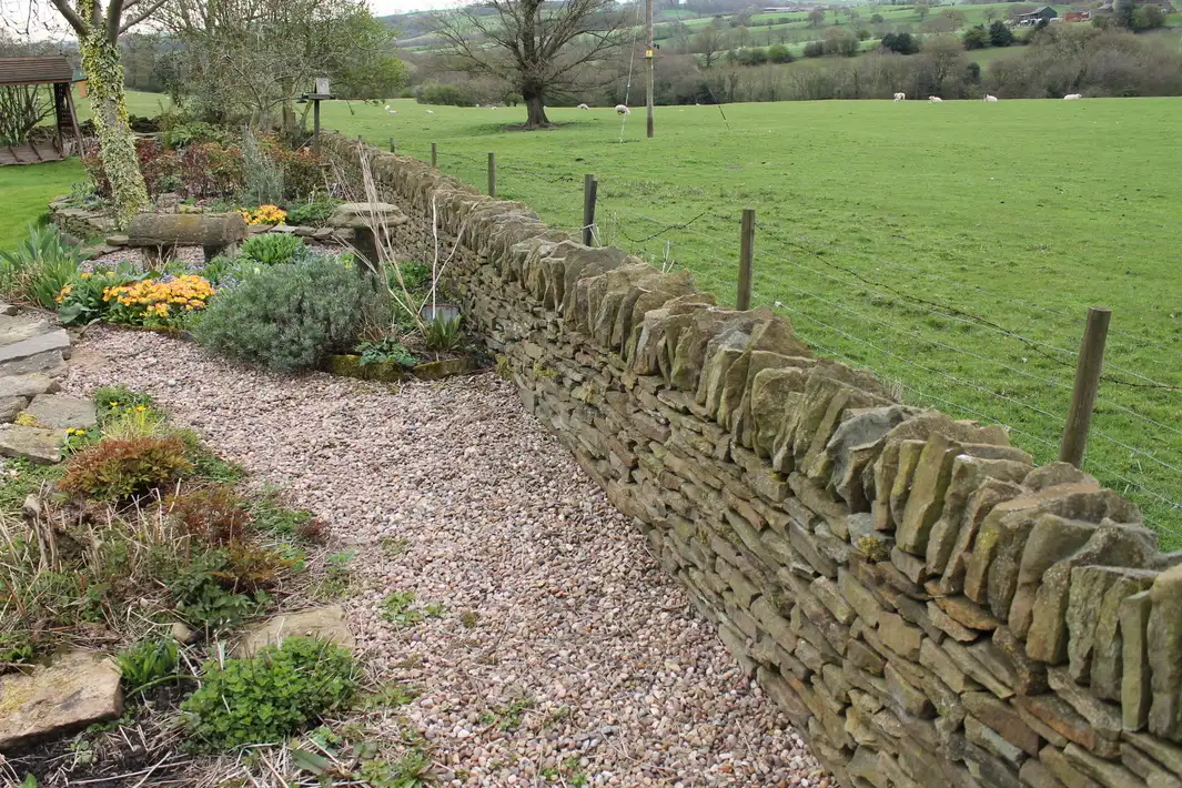 A stone brick wall made with reclaimed stone and boulders