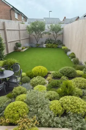 AI Generated Designs Flowers, plants, clean grass, and a seating area tucked away within the flower border create order and comfort in this small garden.